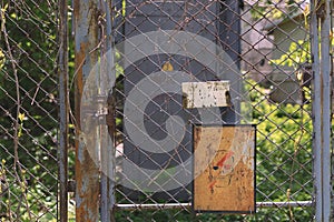 Danger. Fence from the grid overgrown with branches. There is a lock on the door.