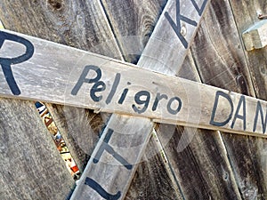 Danger keep out peligro sign painted on wood fence