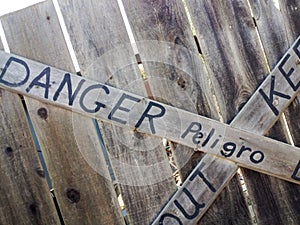 Danger keep out peligro sign painted on wood fence photo