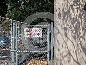 Danger keep out sign behind a residential chain link fence in residential area