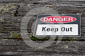 Danger, keep out warning sign over old weathered rustic wooden t
