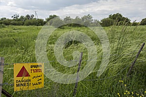 `Danger Mines` yellow warning sign, in Hebrew, Arabic and English, next to a mine field