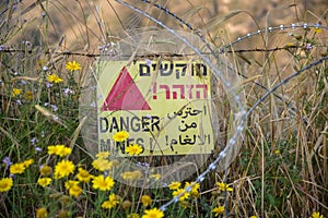 Danger mines - yellow warning sign next to a mine field, close to the border with Syria, in the Golan Heights, Israel