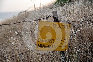 Danger mines - yellow warning sign next to a mine field, close to the border with Syria, in the Golan Heights, Israel