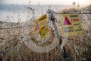 Danger mines - yellow warning sign next to a mine field, close to the border with Syria, in the Golan Heights, Israel