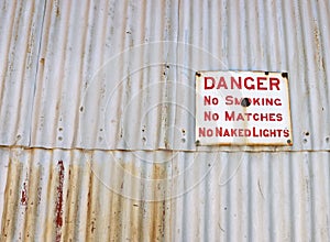 Danger, No Smoking sign on corrugated iron fence