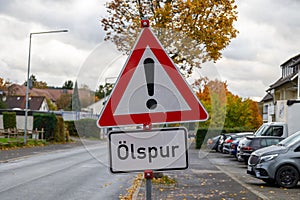 Danger from oil slick: warning sign on the side of the road