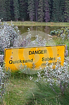 A danger quicksand sign with a pond in the background