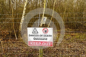 Danger quicksand sign on a wire fence.
