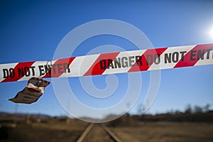 Danger red and white tape barricade exclusion zone area with written authorised personnel entry only on train track photo