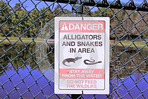 Danger sign Alligators and Snakes posted by a lake at a park in Florida