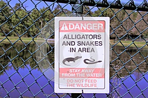 Danger sign Alligators and Snakes posted by a lake at a park in Florida photo