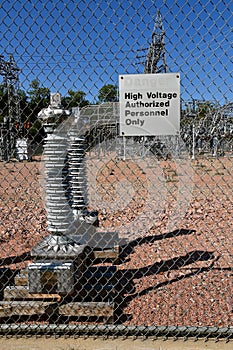 A `Danger` sign in front of a fence of a utility company