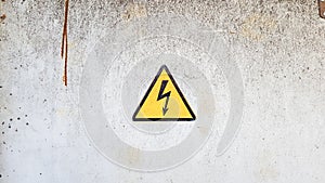 Danger sign of high voltage electricity. Yellow triangular sign with a lightning in the center. This warning is written on an old