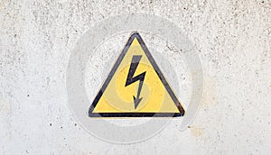 Danger sign of high voltage electricity. Yellow triangular sign with a lightning in the center. This warning is written on an old