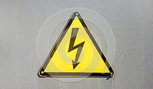 Danger sign of high voltage electricity. Yellow triangular sign with a lightning in the center. This warning is written on an old