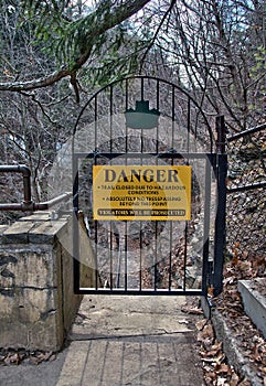 Danger sign and iron gate blocking nature trail