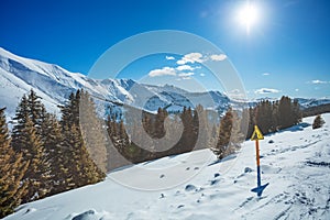 Danger sign on the side of a mountain ski track over high peaks