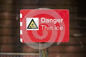 Danger thin ice safety sign at lake in winter