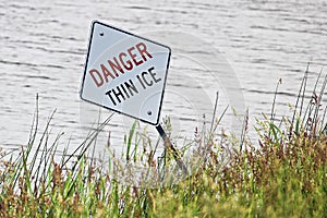 A danger thin ice sign along the shore in summer