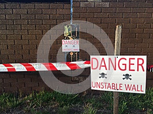 Danger unstable wall sign beside a boundary wall photo