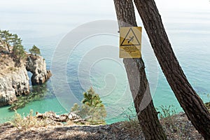 Danger varning sign on a pine tree nera the ocean. Attention to the precipice. Sign for the safety of hikers Crozon, France 29 May