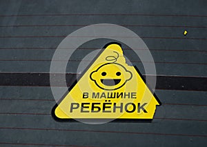 Danger warning sign on a car glass. Translate: Baby in a car.