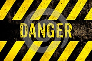 Danger warning sign text with yellow and black stripes painted over concrete wall surface facade texture background