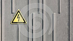 Danger yellow electricity sign on grey plastic background. Power, electricity warning sign