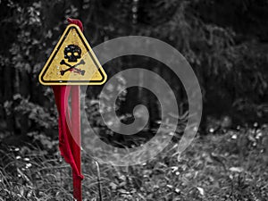 a danger zone sign in the forest next to the road, warning that the area is mined. Wartime concept. gray background