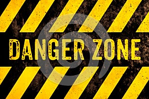 Danger zone warning sign text with yellow and black stripes painted over concrete wall surface facade cement texture background