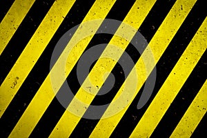 Danger zone: Warning sign yellow and black stripes painted over concrete wall coarse facade with holes and imperfections texture