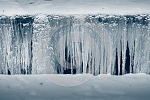 Dangerous abyss in the snow with long icicles