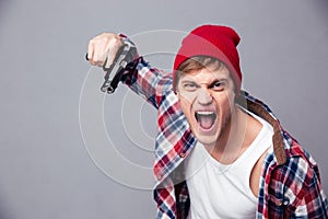 Dangerous agressive young man shouting and threatening with gun