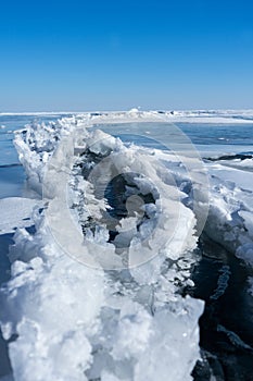 A dangerous crack in the ice of a frozen bay in winter. Open cracked ice on the lake.