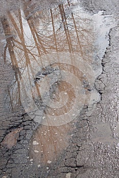 Dangerous destroyed roadbed. The bad asphalted road. Big pothole filled with water.