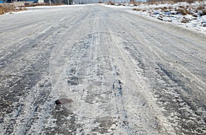 Dangerous driving conditions. Icy road with tracks from the wheels of cars . The concept of safe driving on a winter slippery