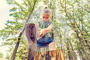 Dangerous and formidable girl chopping wood with an ax and looking angrily into the camera