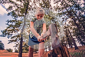 Dangerous and formidable girl chopping wood with an ax and looking angrily into the camera