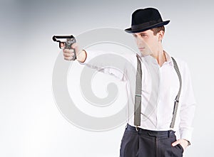 Dangerous gangster in hat aims a pistol