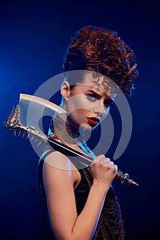 Dangerous girl with sharp axe on dark blue background.