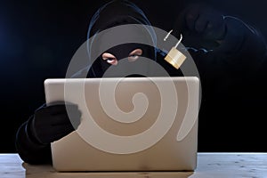 Dangerous hacker man with computer and lock hacking system in cyber crime concept