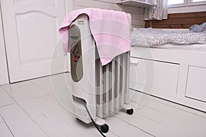 A dangerous hazardous situation with mobile oil heater covered with a towel, that is dryin on a hot electrical device