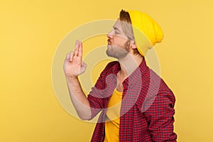 Dangerous hooligan hipster man in beanie hat and checkered shirt pointing up finger gun, blowing smoke