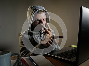 Dangerous looking hacker man in hoodie hacking internet computer system pointing his eyes warning about his ability to break passw photo