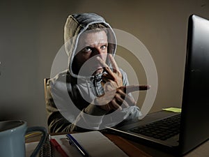 Dangerous looking hacker man in hoodie hacking internet computer system pointing his eyes warning about his ability to break passw