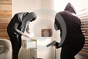 Dangerous masked criminals with weapon stealing money photo