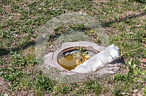 Dangerous opened manhole hole cover, danger for people who walking on the grass in the park in the city