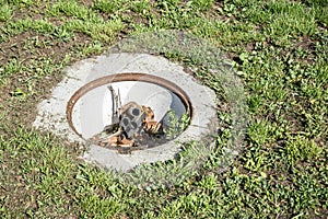 Dangerous opened manhole hole cover, danger for people who walking on the grass in the park in the city