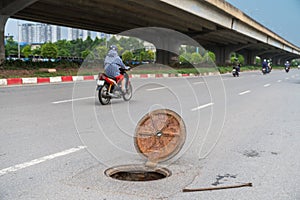 Dangerous opened manhole hole cover, opened sewerage hatch with traffic on background